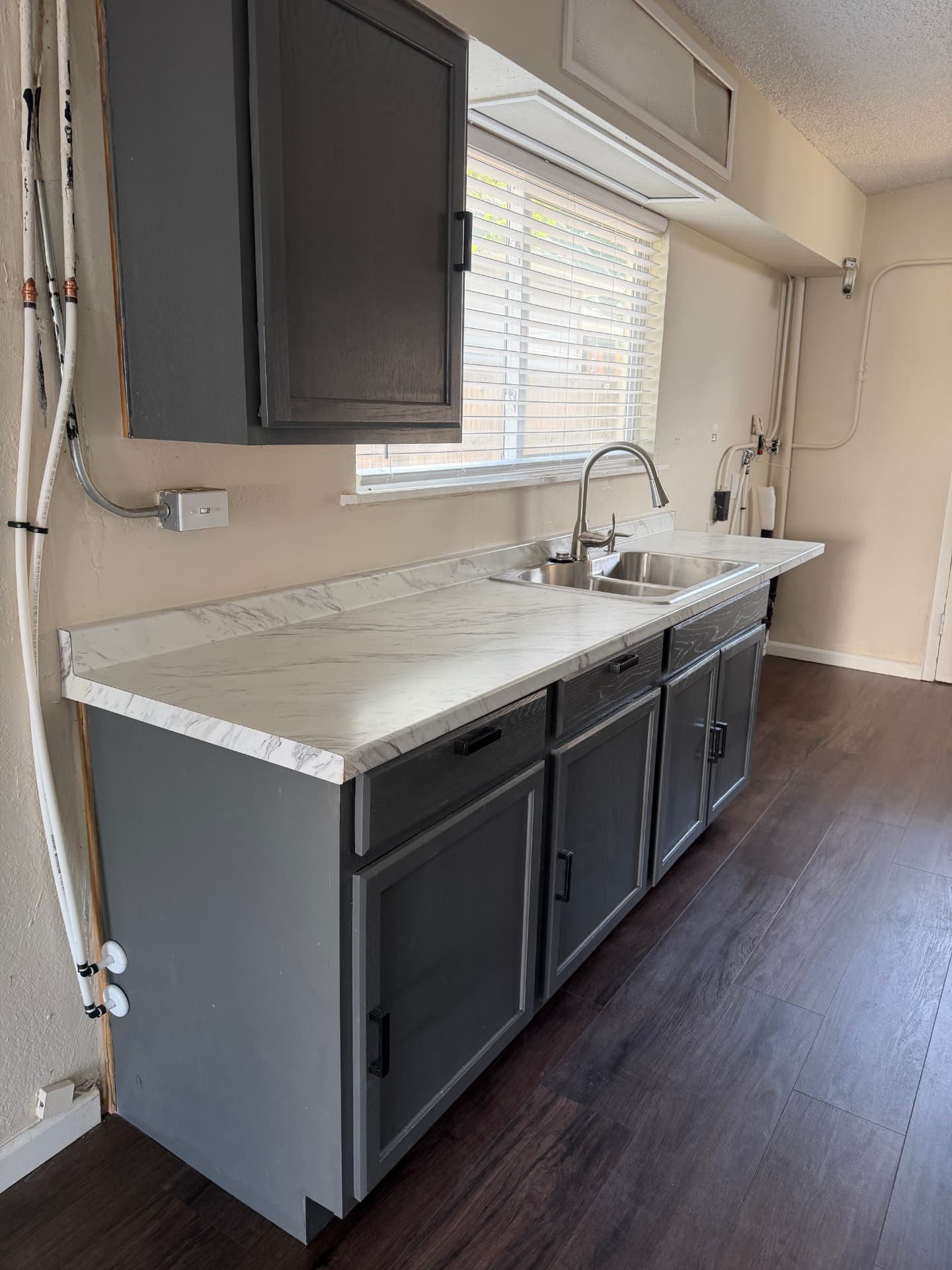 Kitchen cabinets and counters above completed dark wood-look plank flooring