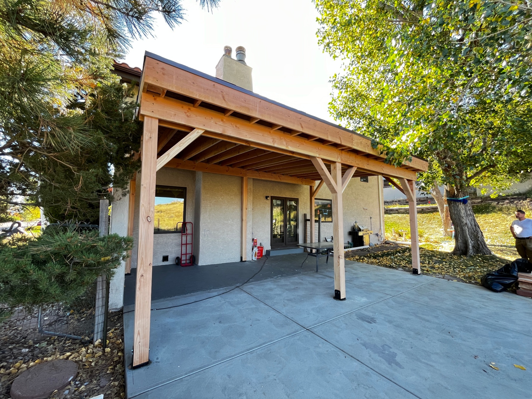 Cedar covered patio with timber posts and brackets attached to stucco home