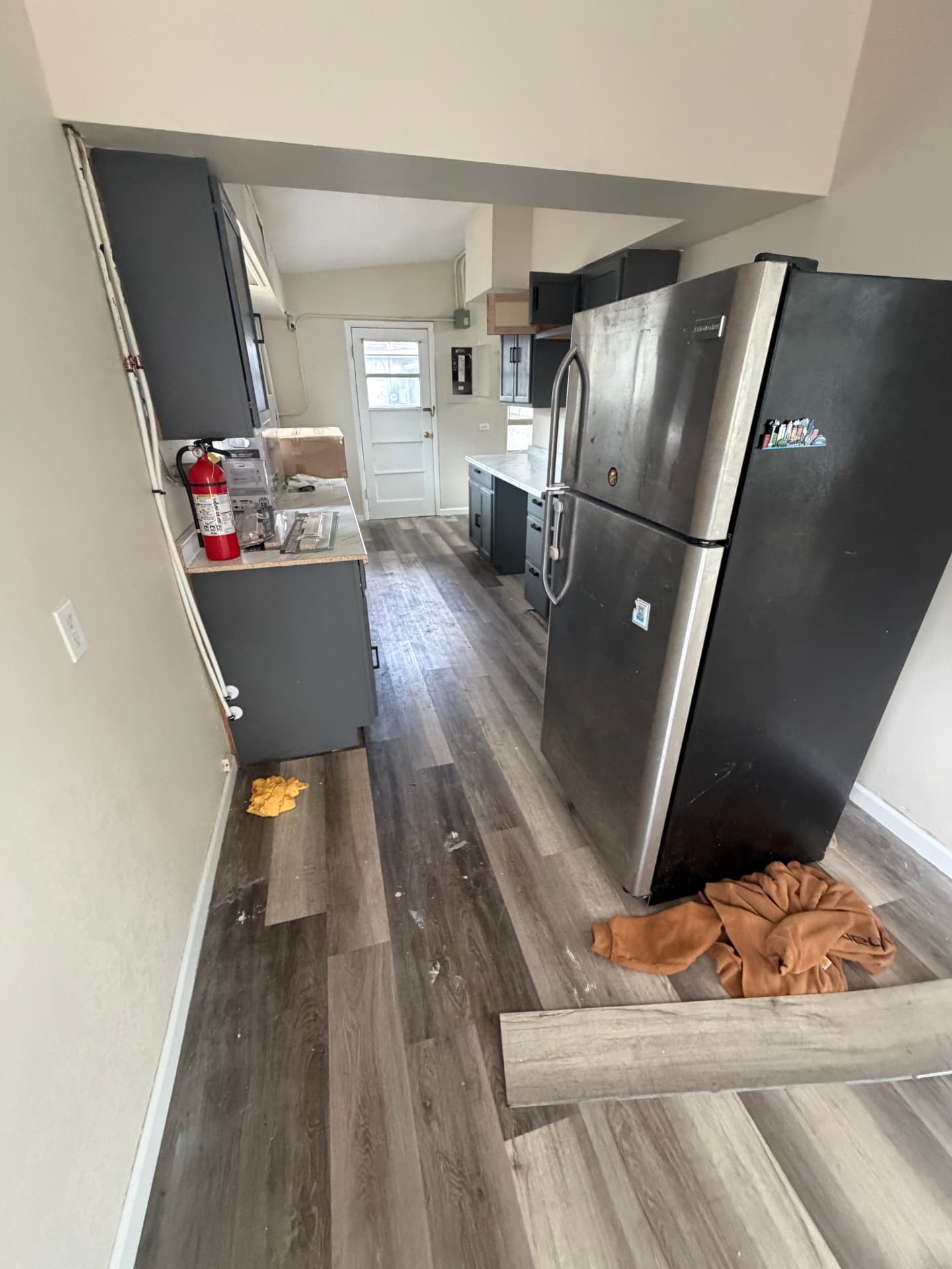 Kitchen during installation with gray wood-look flooring partially in place