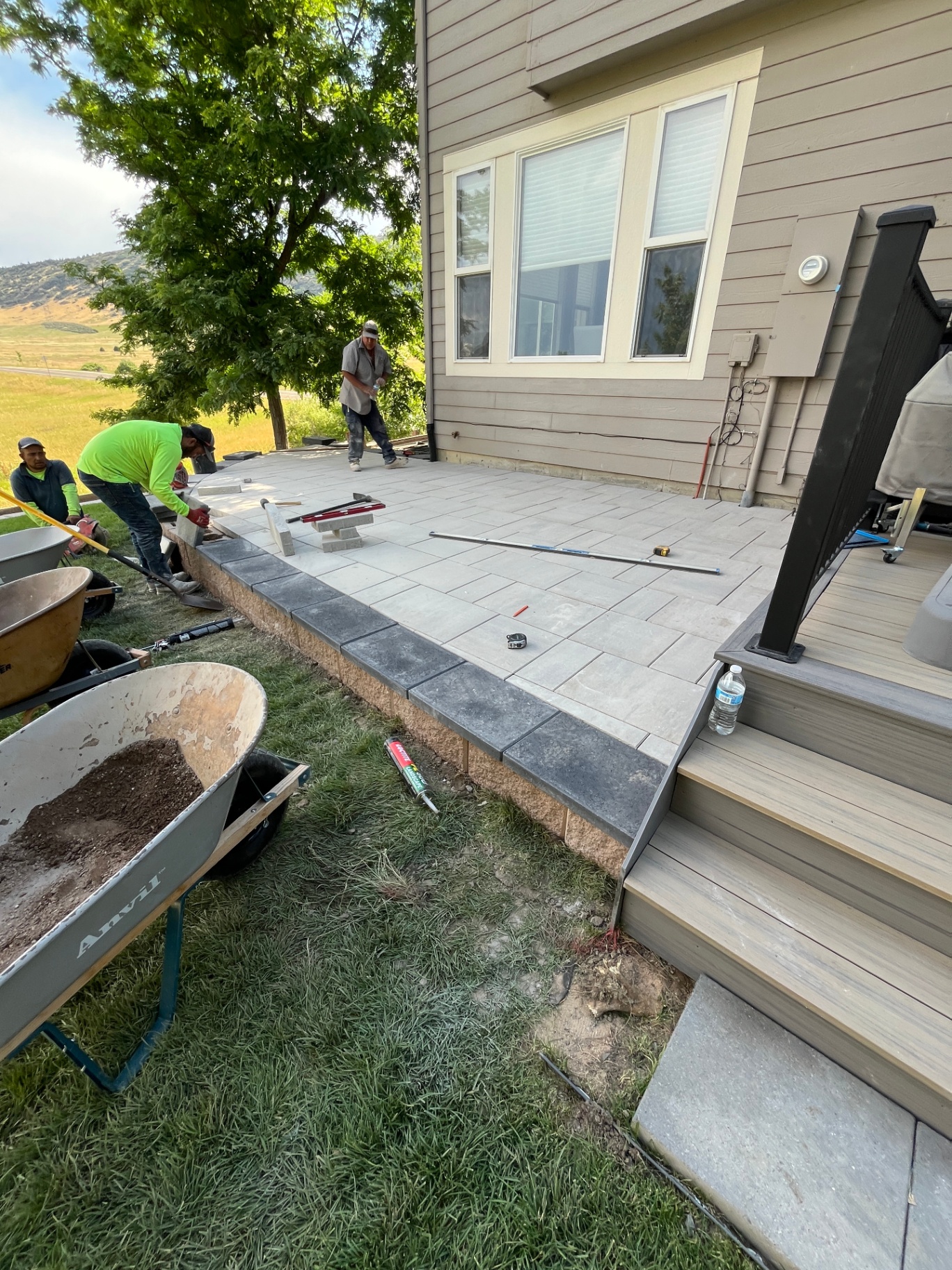 Vitanov crew installing pavers and charcoal border coping on a raised patio