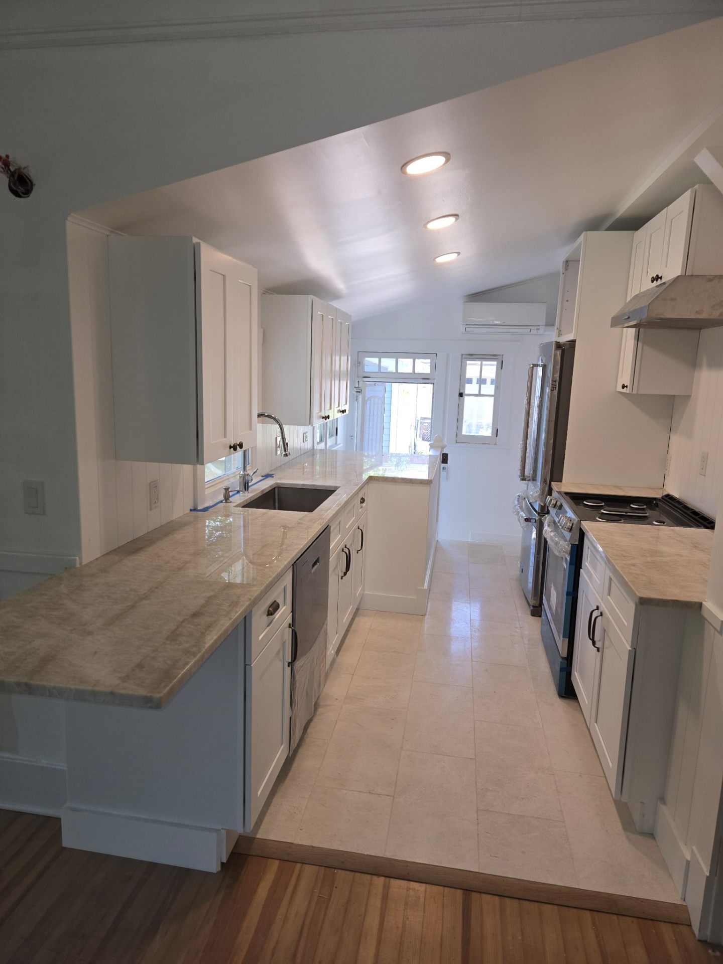 Renovated galley kitchen with white shaker cabinets and quartz countertops