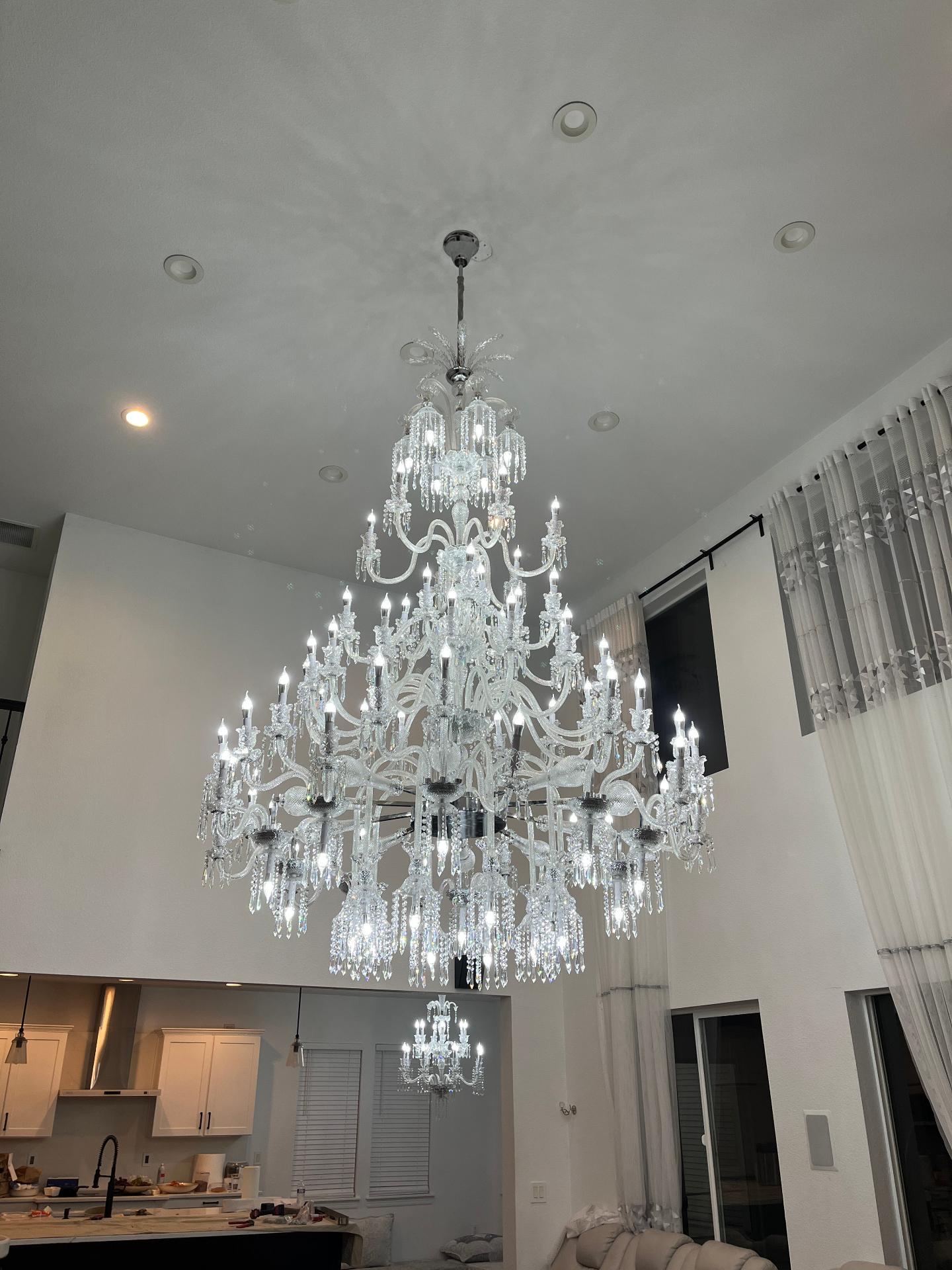 Large crystal chandelier fully installed and illuminated above the open living space