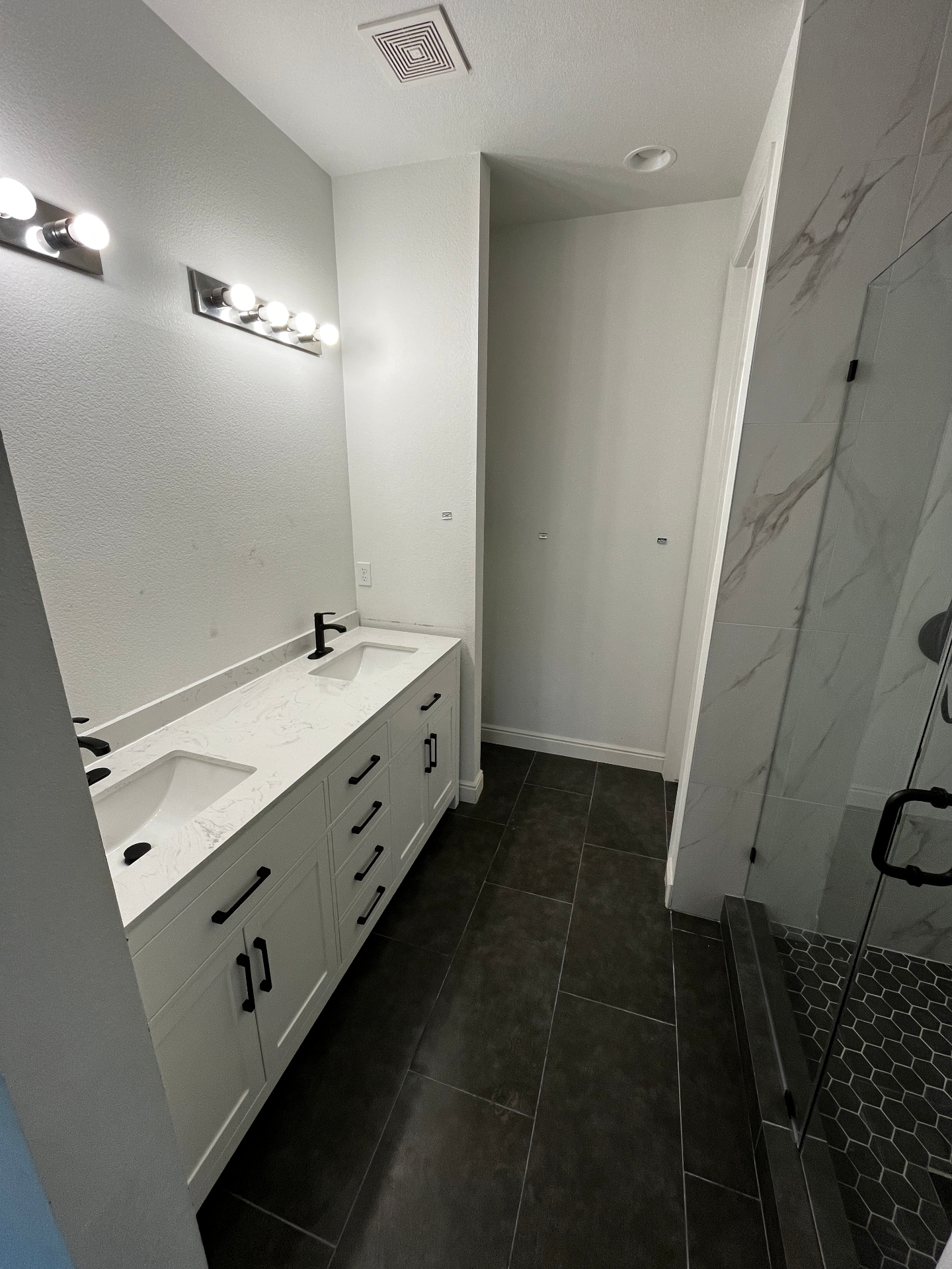 Double vanity bathroom with quartz top, matte black fixtures, and tile floor