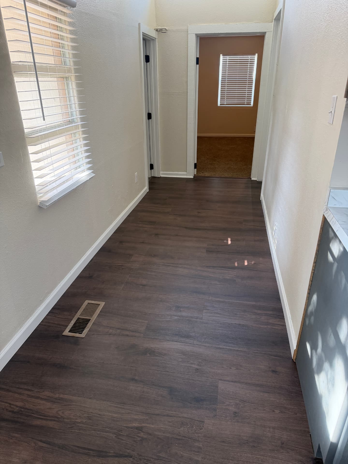 Connecting hall with completed dark wood-look plank flooring and white base trim