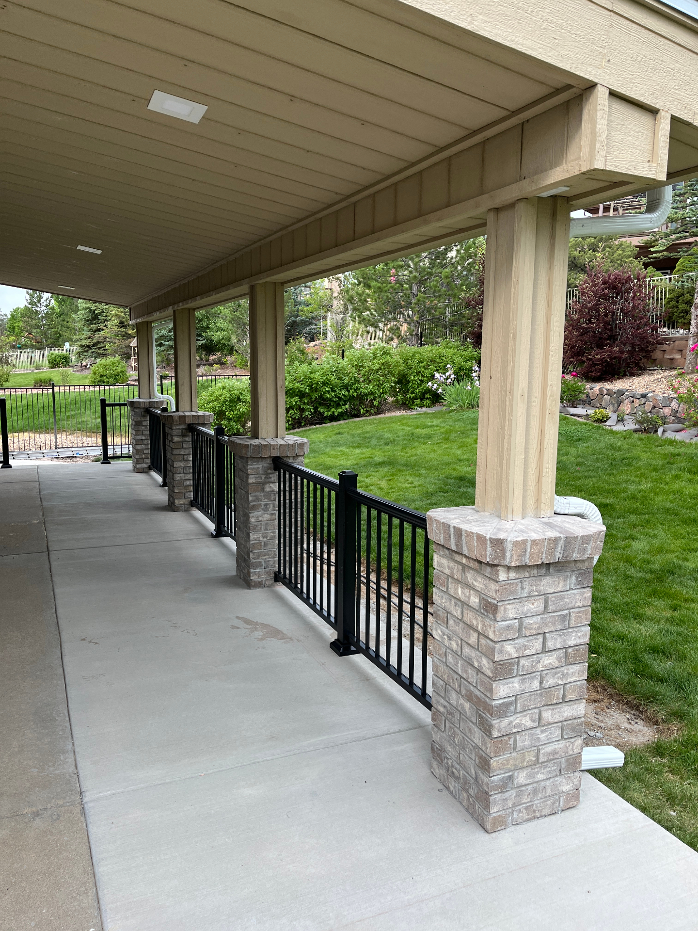 View from under a finished covered patio showing posts, masonry bases, and railings