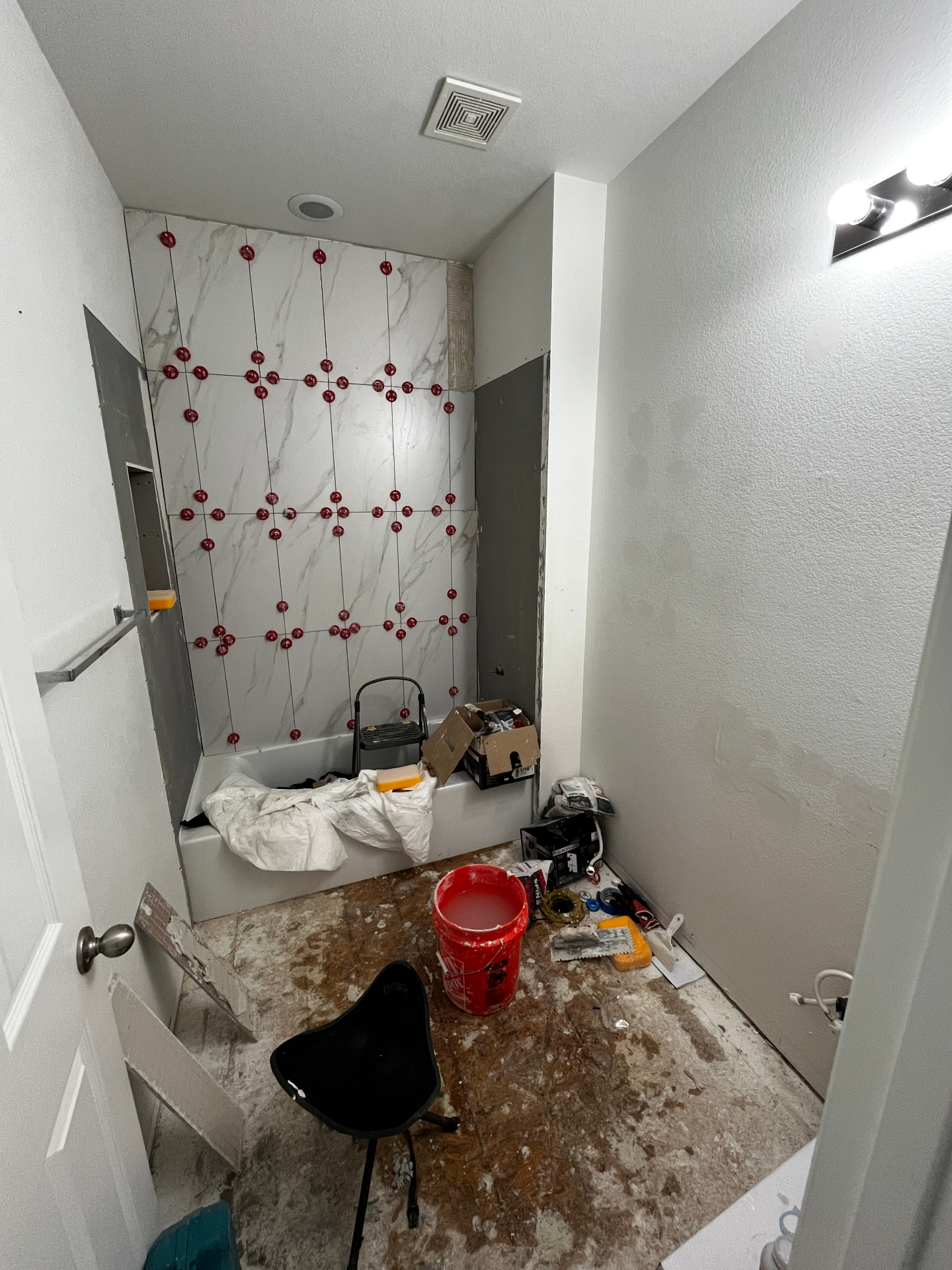 Bathroom remodel in progress with large wall tile being installed