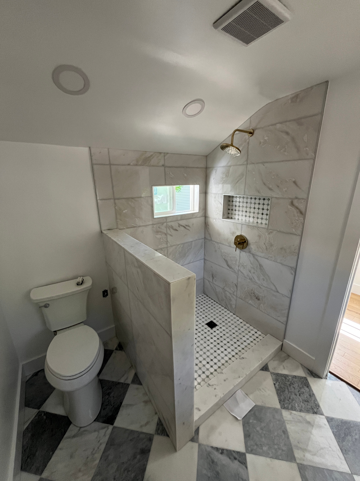 Marble-tiled walk-in shower with brass fixtures and checkerboard floor