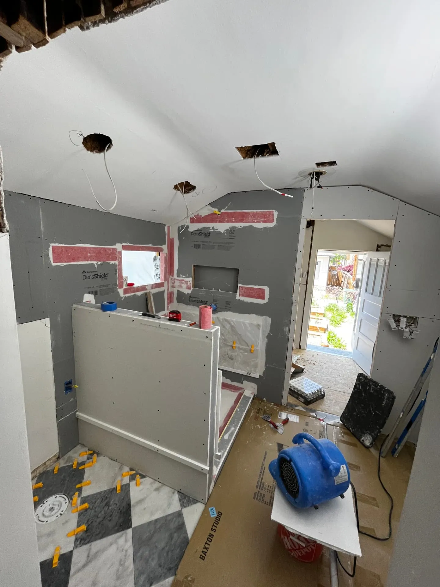 Bathroom remodel in progress with DensShield backer board, waterproofed niche, and marble checkerboard floor tile being set
