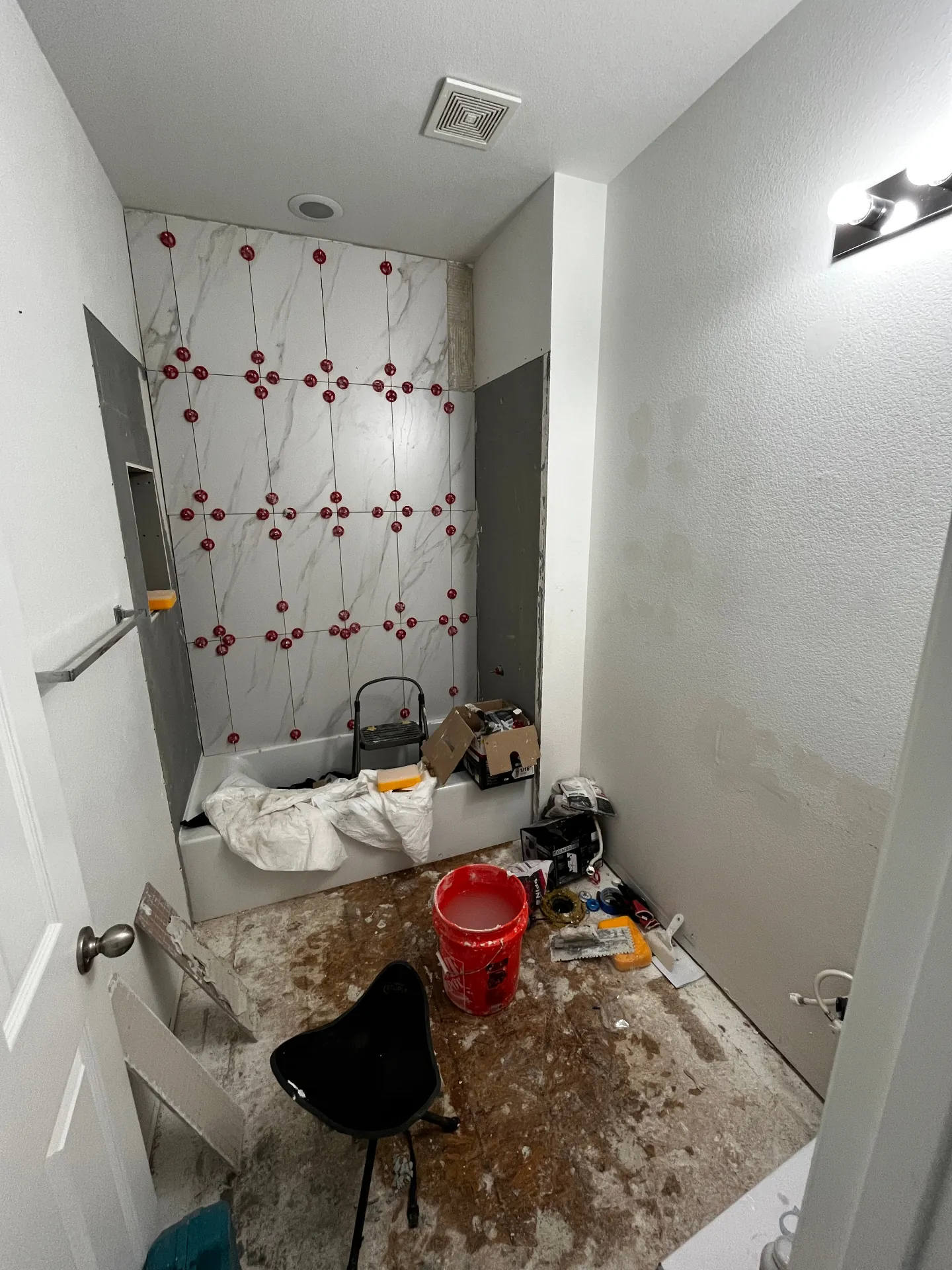Bathroom remodel in progress with large wall tile being installed