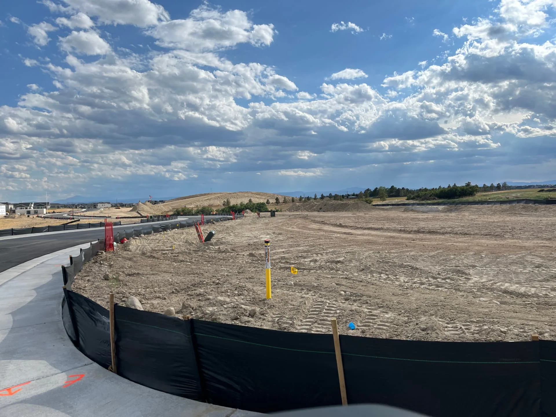Rough-graded lot with silt fence erosion control along a new concrete curb