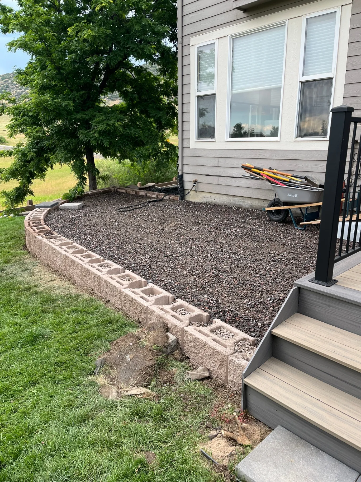 Raised paver patio area with retaining wall block and compacted gravel base ready for paver install