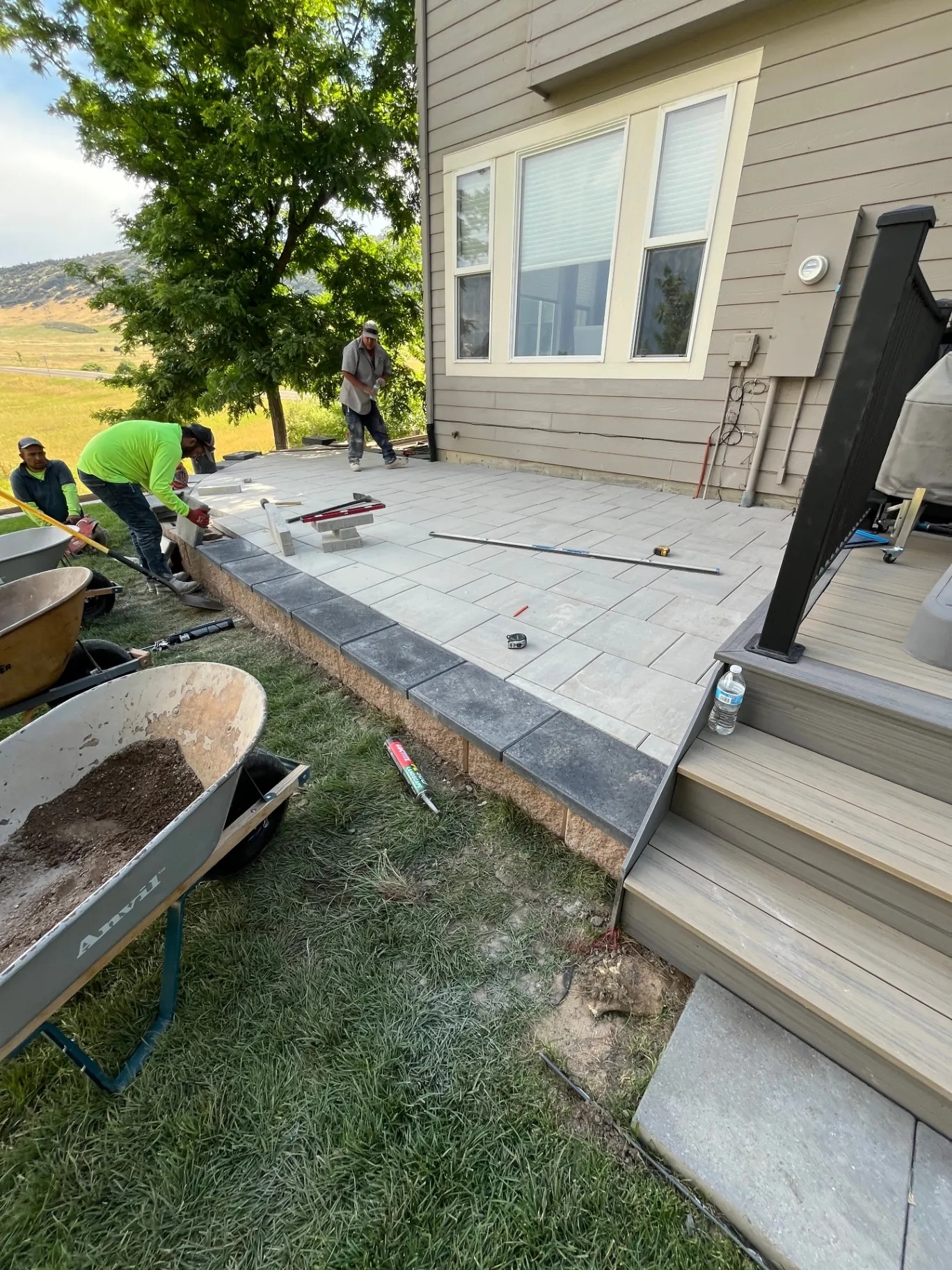 Vitanov crew installing pavers and charcoal border coping on a raised patio