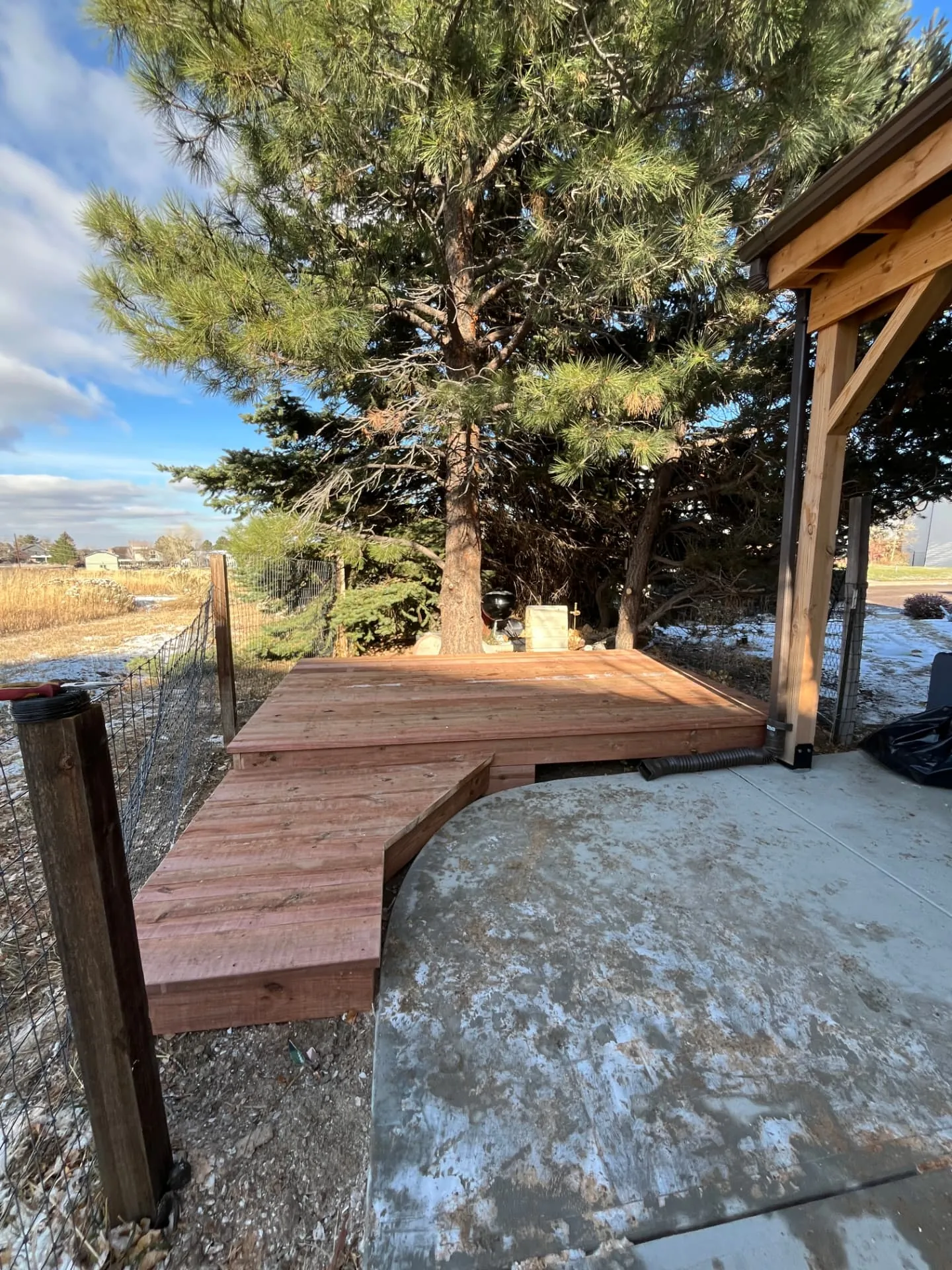 Finished redwood deck with wrap-around step platform tying into a curved concrete patio
