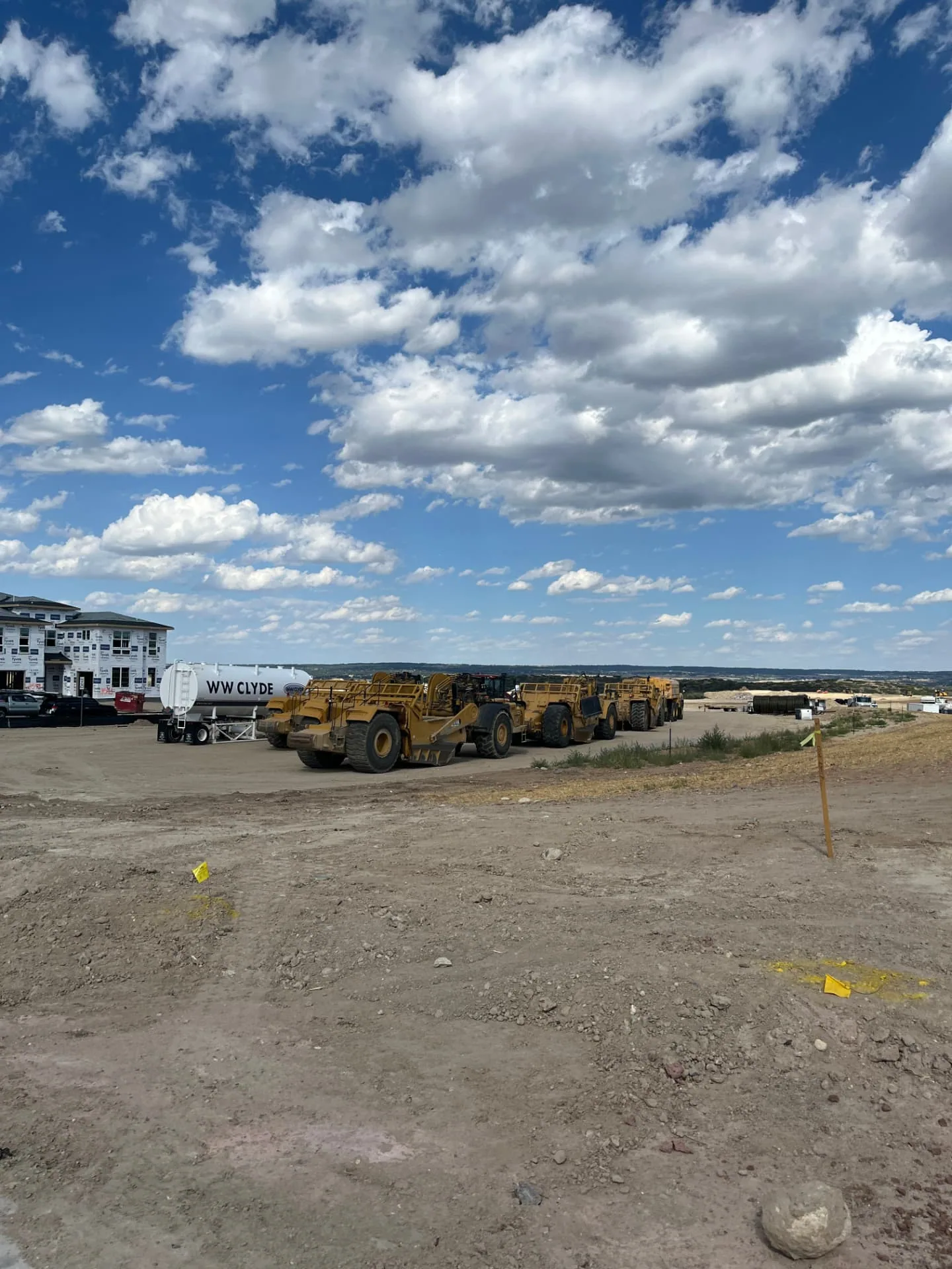 Scrapers and a water truck staged for mass grading and dirt work on a Colorado site