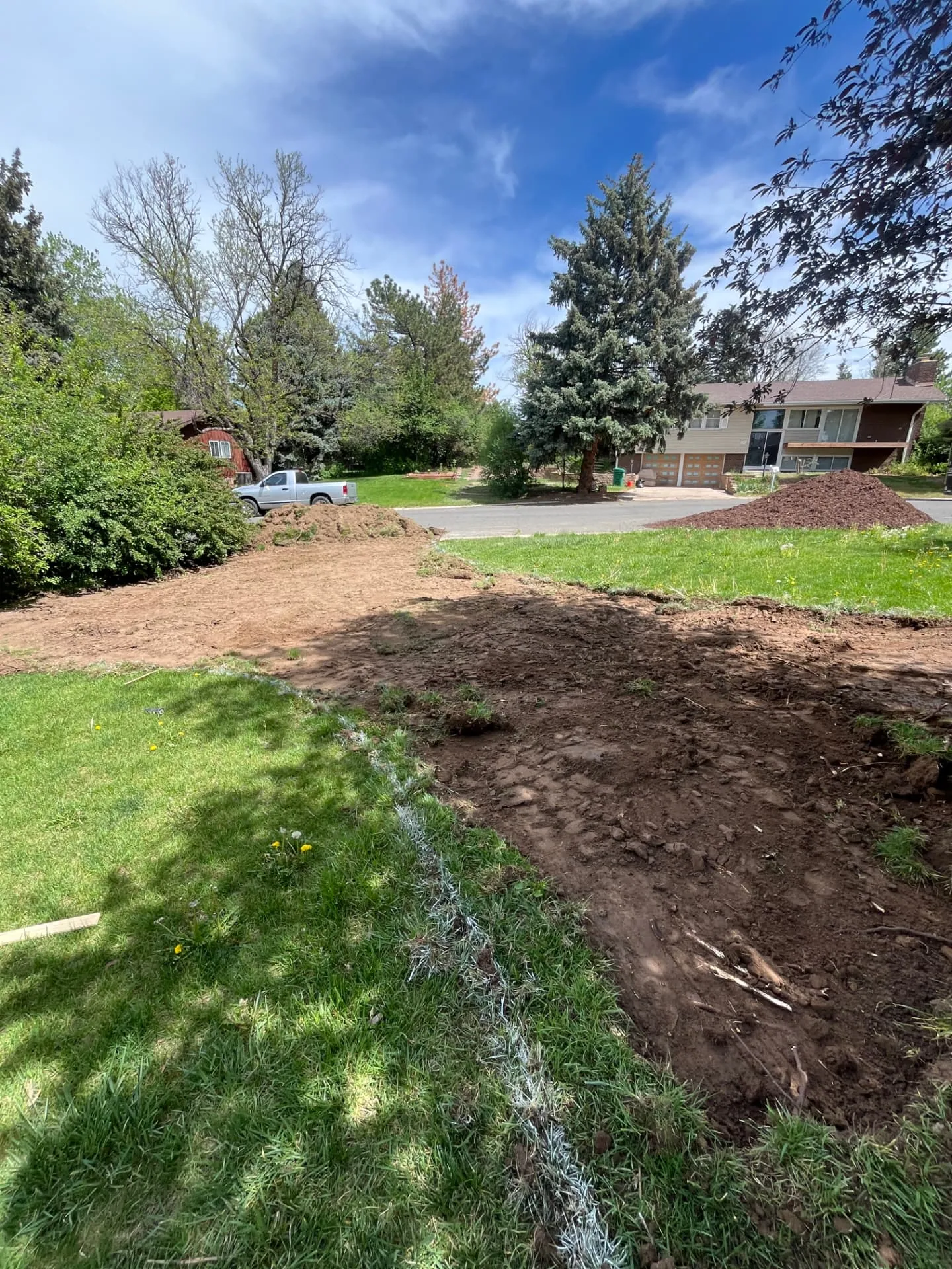 Front yard stripped and rough graded with dirt stockpiles staged at the curb
